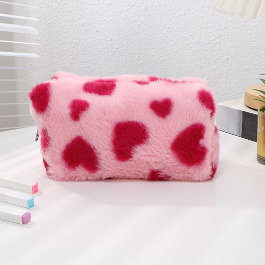 Pink fluffy pouch with red hearts on a white surface